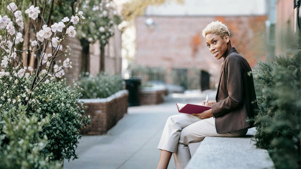 woman sitting in city writing in journal
